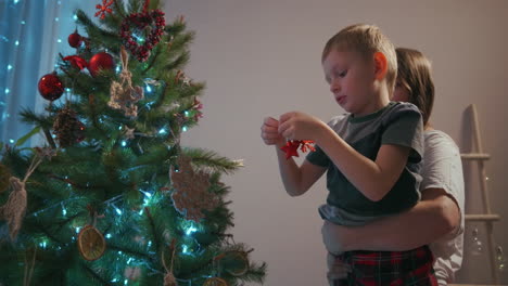 Eine-Mutter-Holt-Ihren-Sohn-Ab,-Um-Einen-Weihnachtsbaum-Zu-Schmücken.-Neujahrsdekorationen-Und-Vorbereitung-Auf-Weihnachten.-Hochwertiges-4K-Filmmaterial